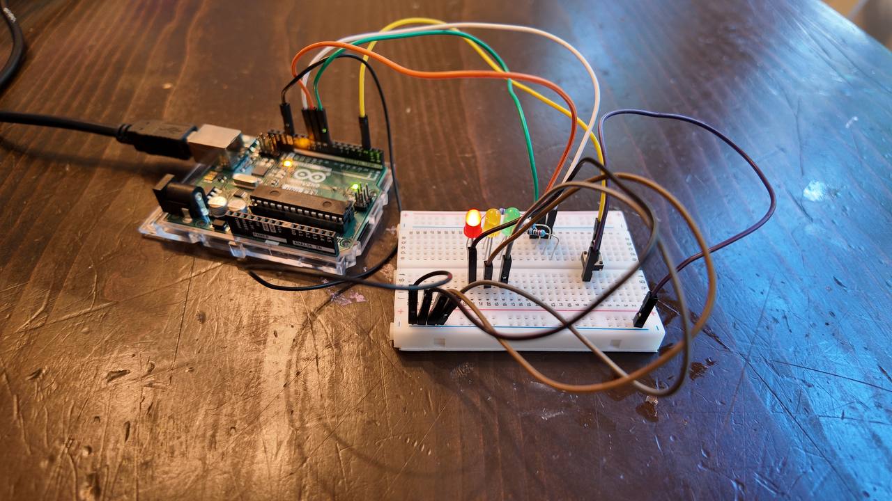 Completed Arduino traffic-light build with an Uno connected to red, yellow, and green LEDs on a breadboard.